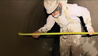 worker taking measurements inside pipe