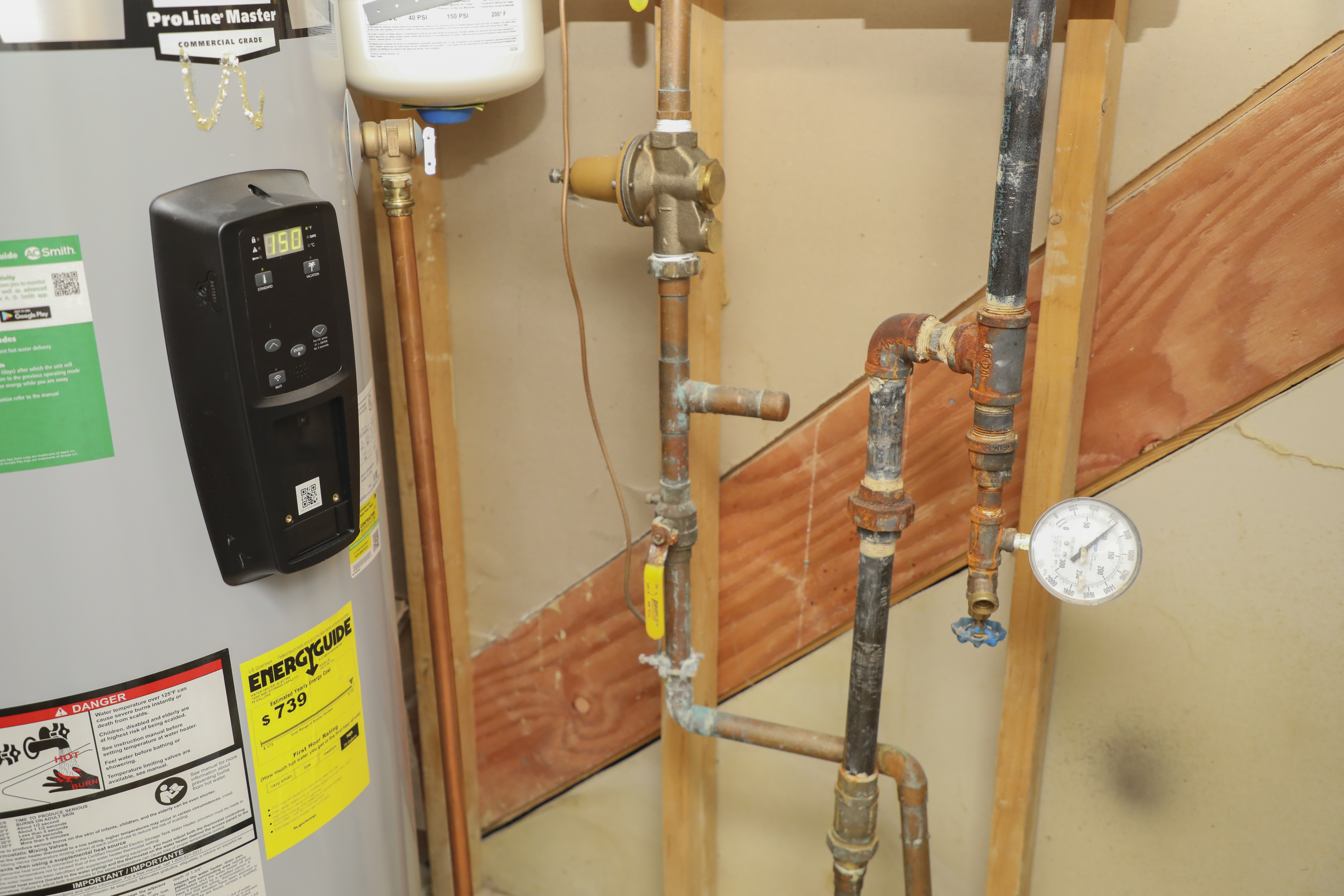 Utility closet with water lines to the fire sprinkler system showing pipes, valve, and gauge