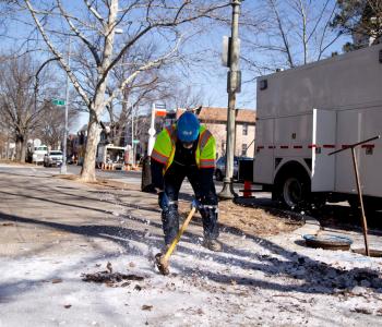 A DC Water employee breaks up ice on a sidewalk