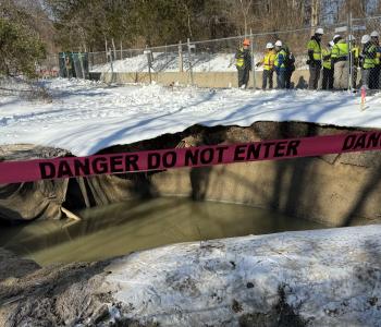Photo of collapse site and federal, state, local officials in background