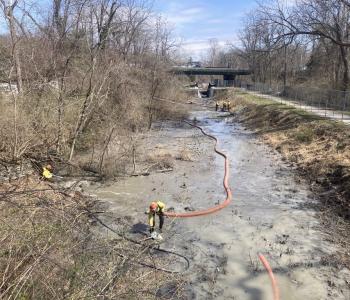 photos of workers with hoses vacuuming out canal