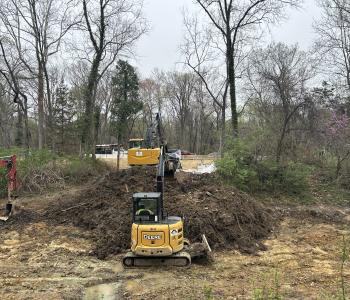 Excavators in the canal digging up soil and another excavator removing the soil to a dump truck to be hauled away 