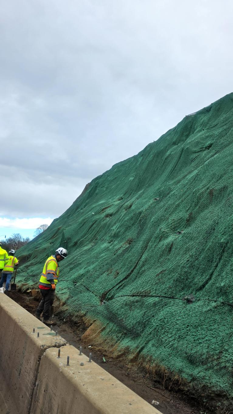 Photo of a worker on the slope an the slope with hydroseeding completed