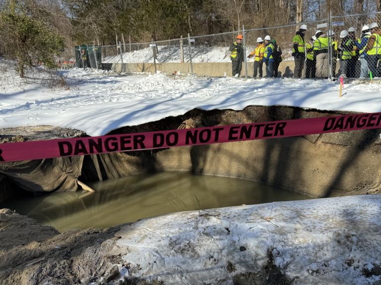 Photo of collapse site and federal, state, local officials in background
