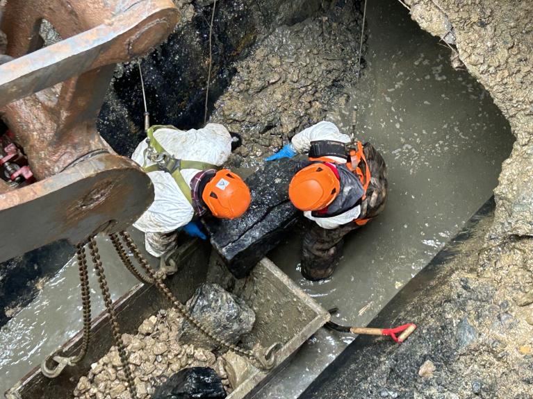 workers removing a large boulder in damaged pipe