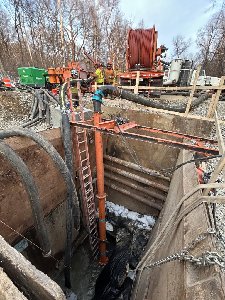 Three workers over the pit accessing the Potomac Interceptor for Cleaning