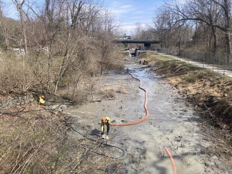 photos of workers with hoses vacuuming out canal