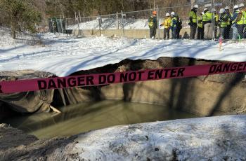 Photo of collapse site and federal, state, local officials in background