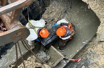 workers removing a large boulder in damaged pipe