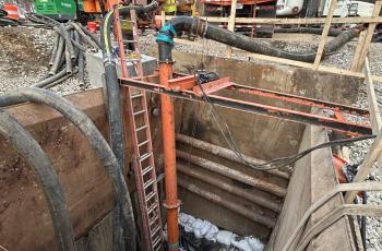 Three workers over the pit accessing the Potomac Interceptor for Cleaning