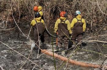 workers spraying and mucking sludge from canal