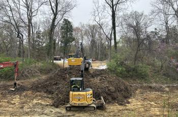 Excavators in the canal digging up soil and another excavator removing the soil to a dump truck to be hauled away 